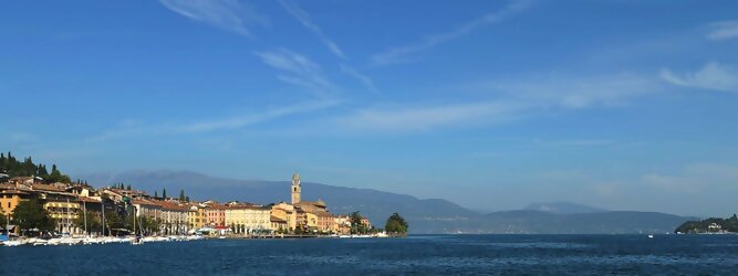 Trip Belgien beliebte Urlaubsziele am Gardasee -  Mit einer Fläche von 370 km² ist der Gardasee der größte See Italiens. Es liegt am Fuße der Alpen und erstreckt sich über drei Staaten: Lombardei, Venetien und Trentino. Die maximale Tiefe des Sees beträgt 346 m, er hat eine längliche Form und sein nördliches Ende ist sehr schmal. Dort ist der See von den Bergen der Gruppo di Baldo umgeben. Du trittst aus deinem gemütlichen Hotelzimmer und es begrüßt dich die warme italienische Sonne. Du blickst auf den atemberaubenden Gardasee, der in zahlreichen Blautönen schimmert - von tiefem Dunkelblau bis zu funkelndem Türkis. Majestätische Berge umgeben dich, während die Brise sanft deine Haut streichelt und der Duft von blühenden Zitronenbäumen deine Nase kitzelt. Du schlenderst die malerischen, engen Gassen entlang, vorbei an farbenfrohen, blumengeschmückten Häusern. Vereinzelt unterbricht das fröhliche Lachen der Einheimischen die friedvolle Stille. Du fühlst dich wie in einem Traum, der nicht enden will. Jeder Schritt führt dich zu neuen Entdeckungen und Abenteuern. Du probierst die köstliche italienische Küche mit ihren frischen Zutaten und verführerischen Aromen. Die Sonne geht langsam unter und taucht den Himmel in ein leuchtendes Orange-rot - ein spektakulärer Anblick.